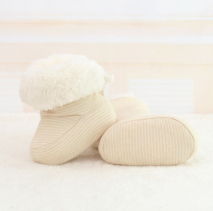 Pair of beige baby socks with white fluffy top on a light background