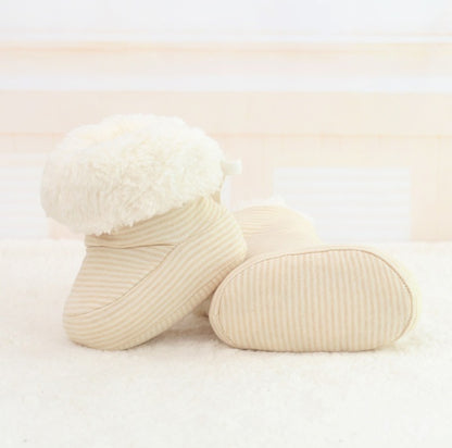 Pair of beige baby socks with white fluffy top on a light background