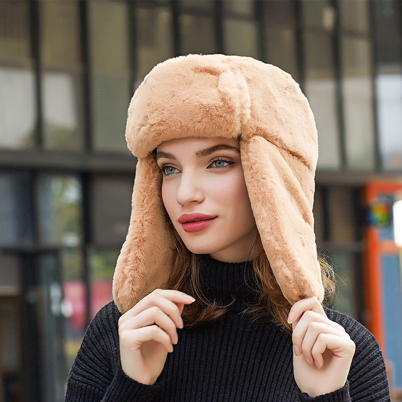 Woman wearing a beige fur hat with ear flaps outdoors