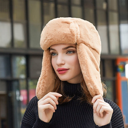 Woman wearing a beige fur hat with ear flaps outdoors