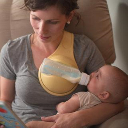 Woman breastfeeding a baby using a yellow哺乳枕 (breastfeeding pillow) while sitting on a couch.
