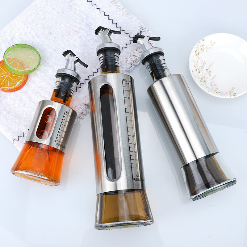 Three olive oil dispensers with measurement scales on a white surface.