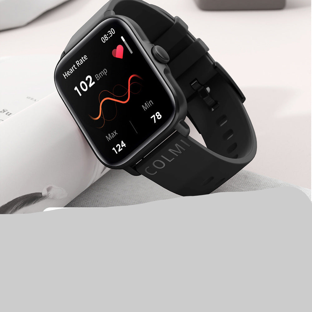 Black smartwatch displaying heart rate on a white surface with a close-up inset of heart rate graph.