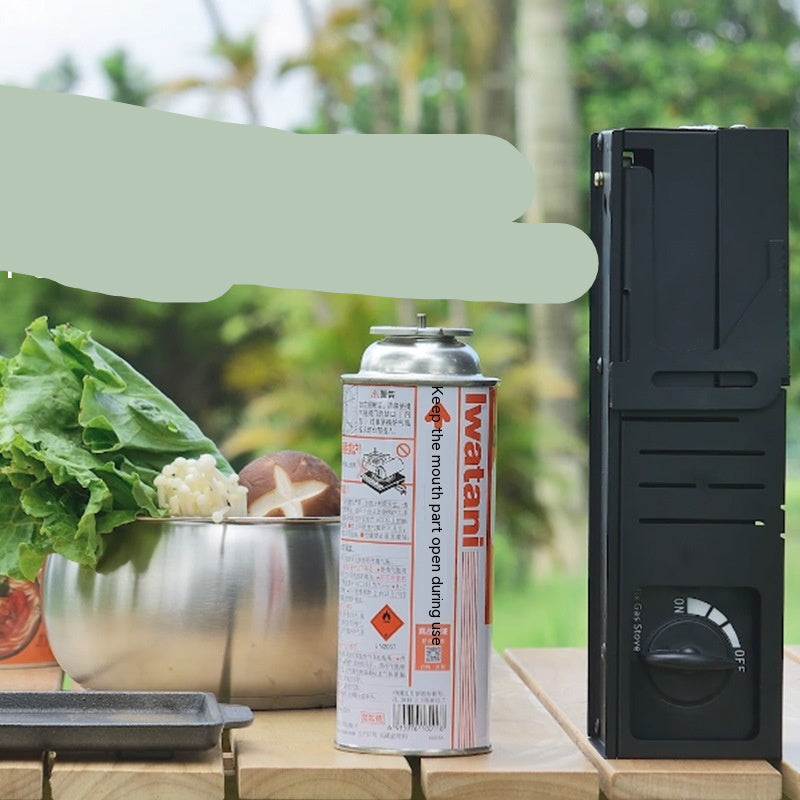 Folding portable cassette stove with Iwatani canister on a wooden surface outdoors