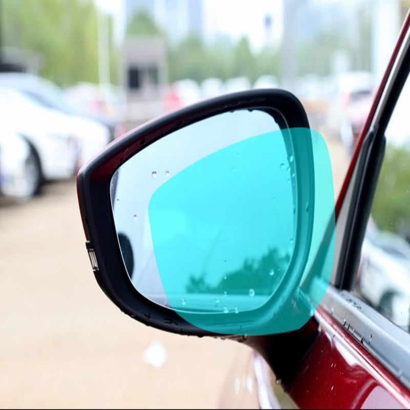 Car side mirror with a blue reflective film on a blurred background of a parking lot.