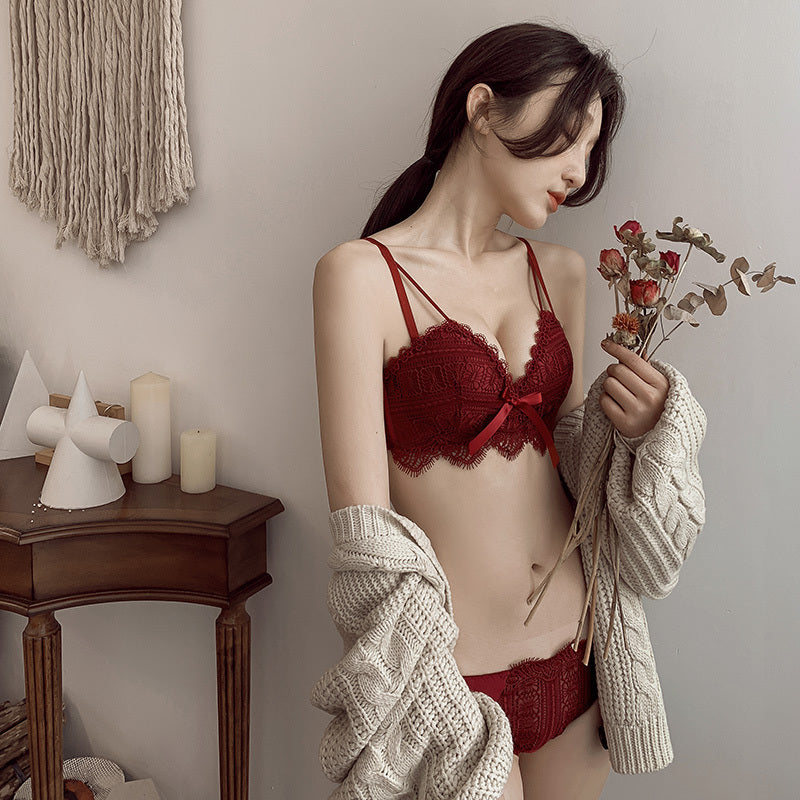 Woman wearing a red bra and underwear set holding flowers indoors.