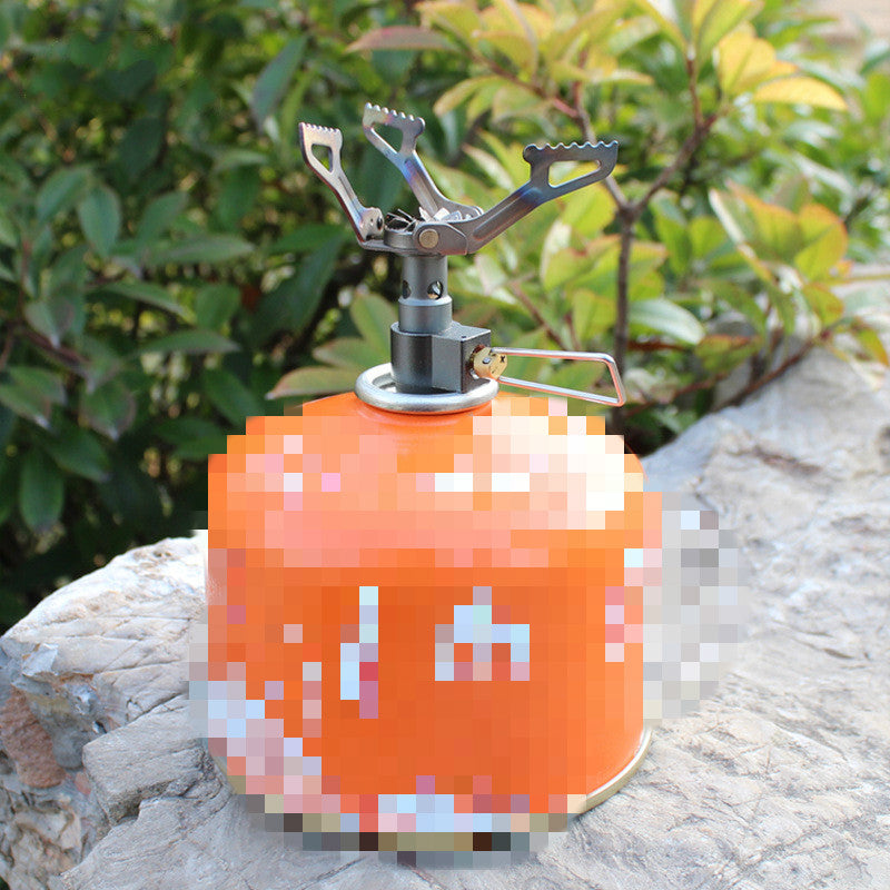 Orange camping stove on a stone surface with green foliage in the background