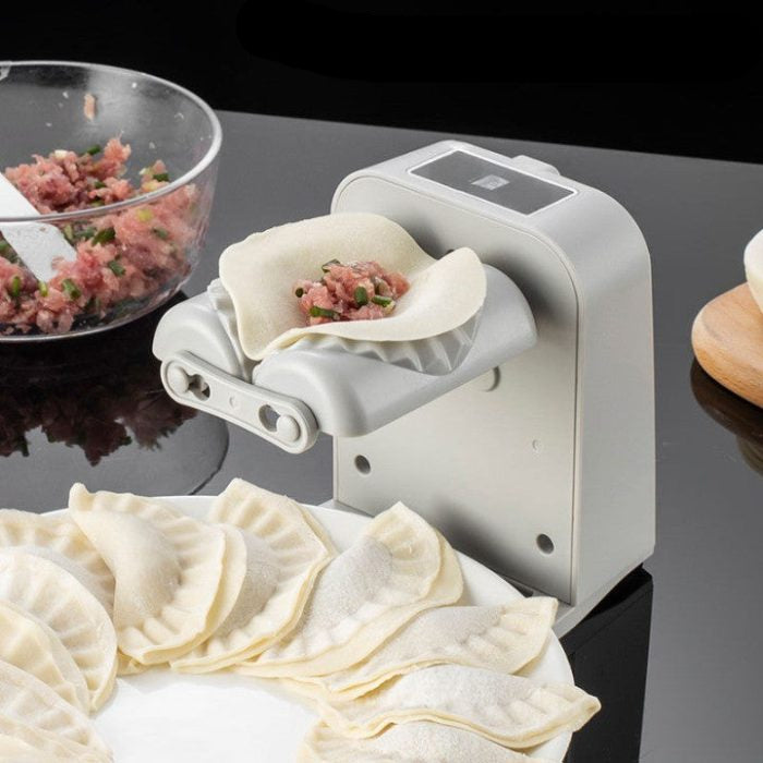 Electric dumpling maker with dumplings and filling on a reflective surface