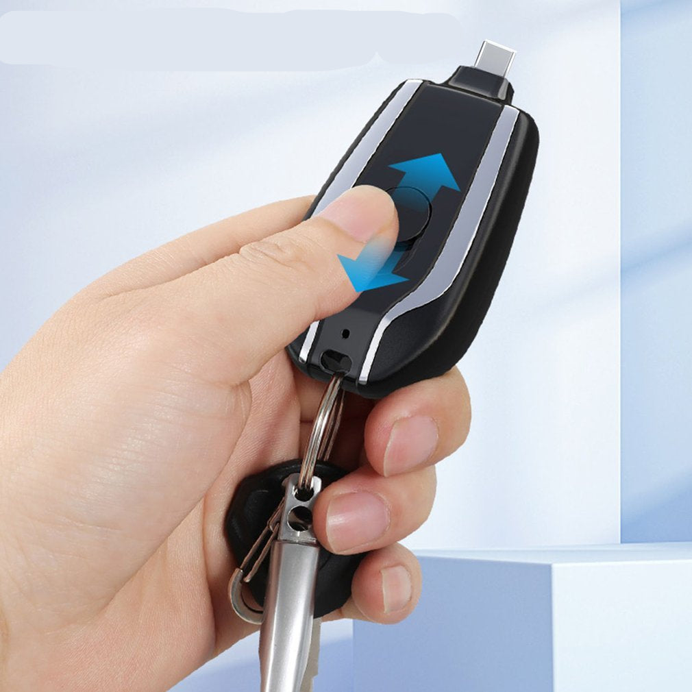 Hand holding a keychain with a telescopic plug design against a light blue background