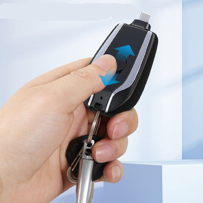 Hand holding a keychain with a telescopic plug design against a light blue background