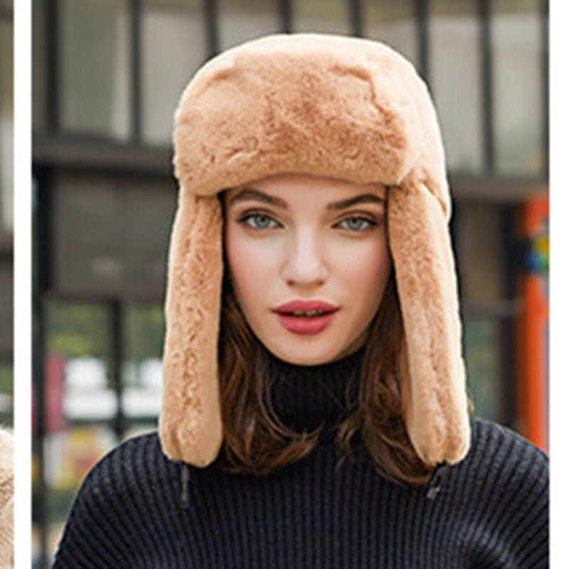 Woman wearing a beige fur hat with ear flaps against an urban background