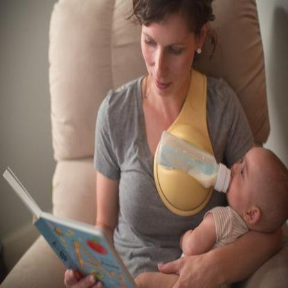 Woman reading a book to a baby while holding a bottle, sitting on a couch.