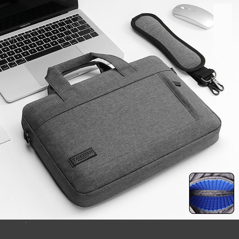 Gray laptop bag with handle and strap next to a laptop and mouse on a white background.