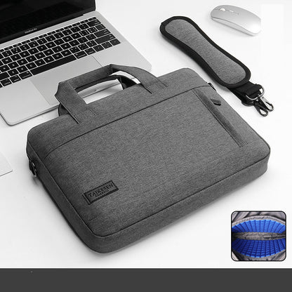 Gray laptop bag with handle and strap next to a laptop and mouse on a white background.