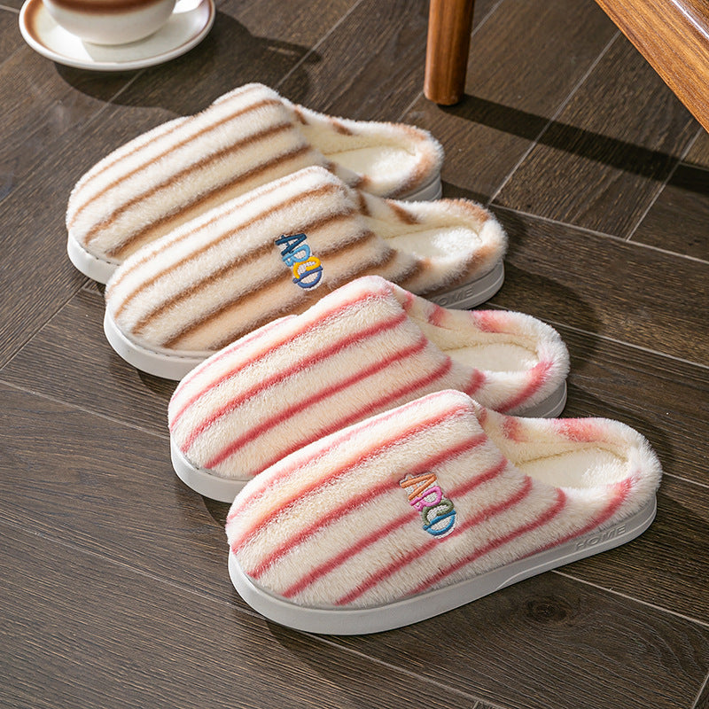Pair of striped slippers on a wooden floor with a cup in the background.