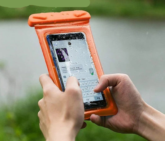 Person using a smartphone with an orange waterproof case outdoors.