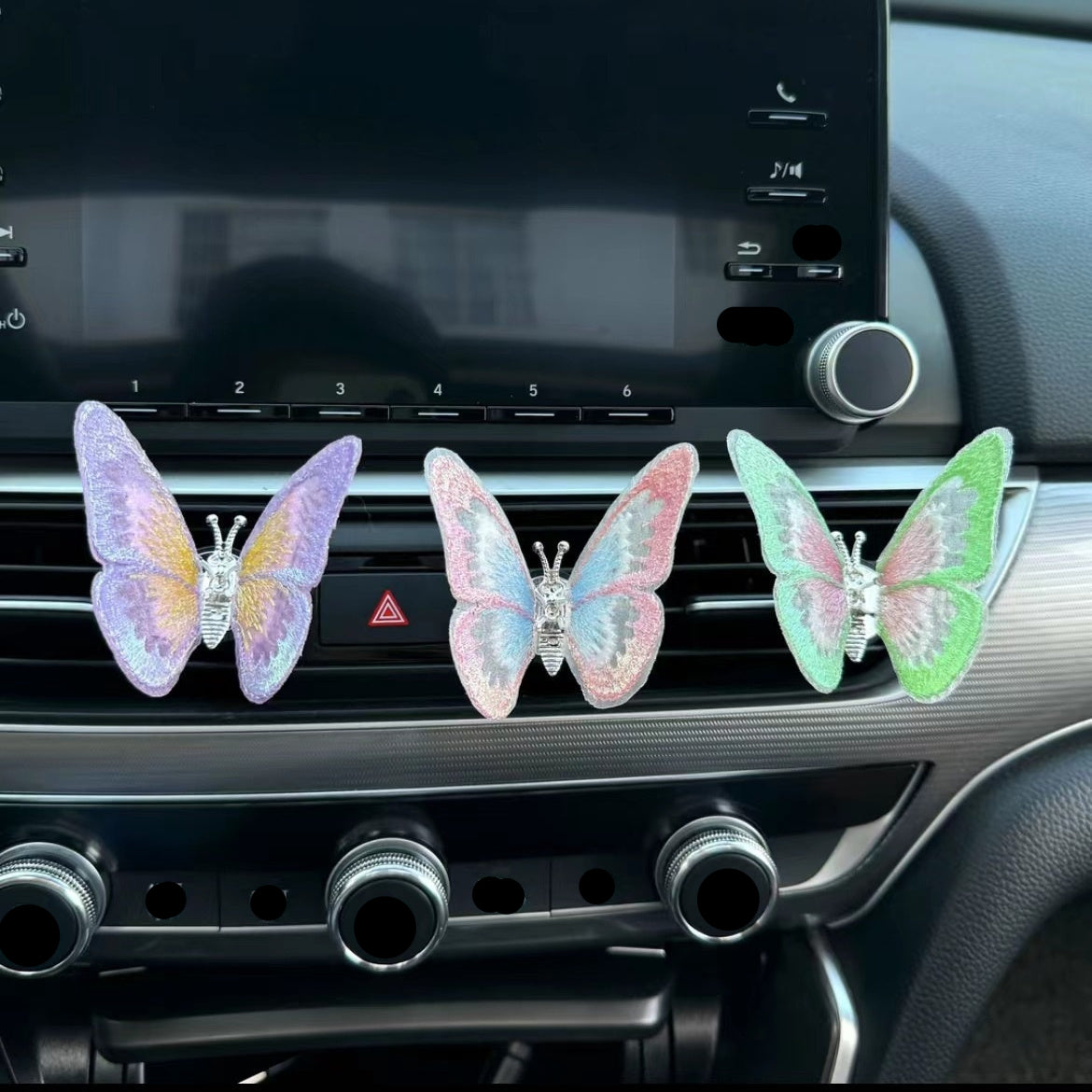 Three colorful butterfly-shaped car air fresheners on a car's air vent.