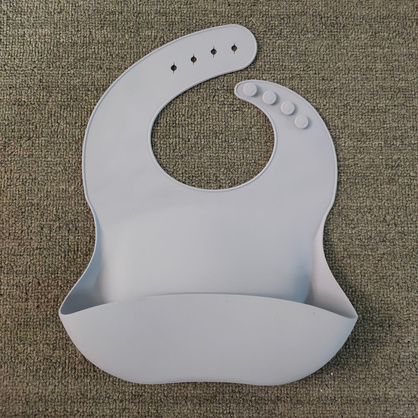 Gray silicone bib on a textured brown surface