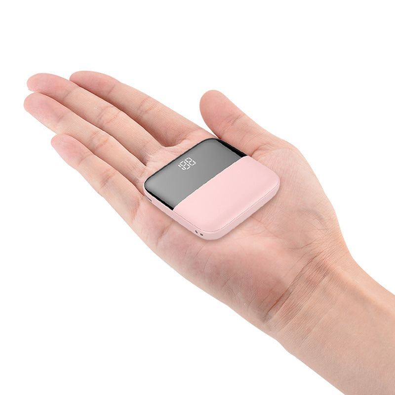 Small pink electronic device held in a hand against a white background
