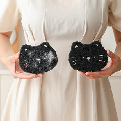 Two black cat-shaped sponges held by a person against a neutral background