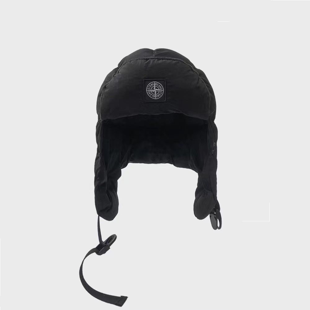 Black winter hat with ear flaps and a brand logo on a light gray background