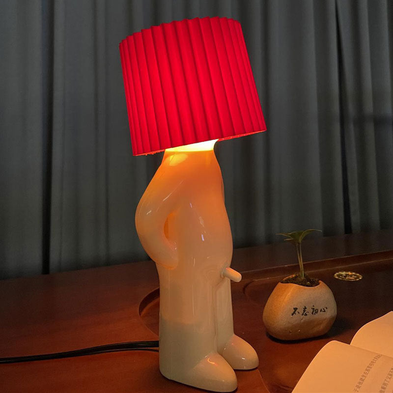 Novelty lamp with a red shade on a wooden surface