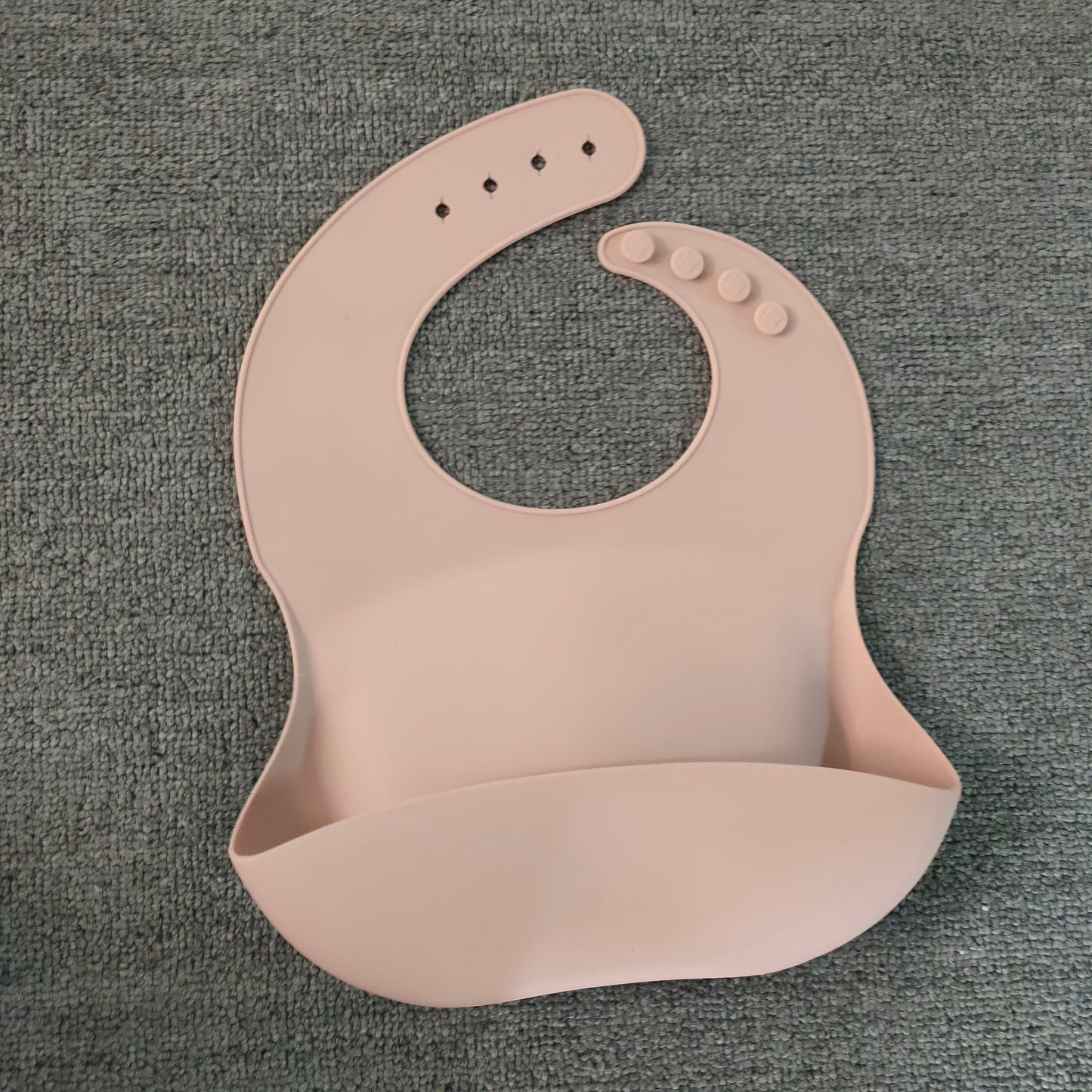 Pink silicone bib on a gray textured background