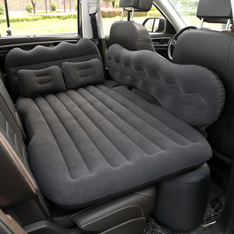 Inflatable car mattress set up in a vehicle with two pillows.