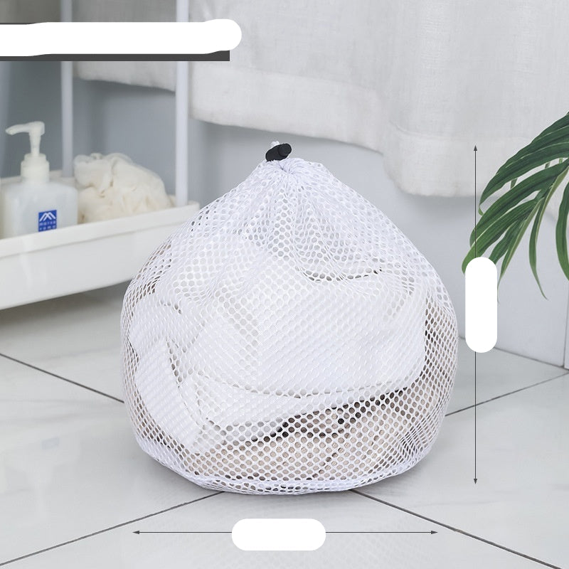 Two white mesh laundry bags filled with laundry standing in front of a washing machine with a person partially visible in the background.