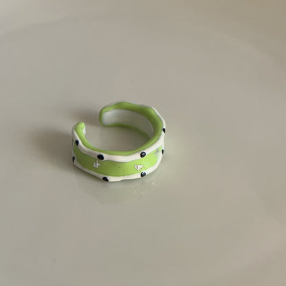 Green ceramic ring with black dots on a beige background