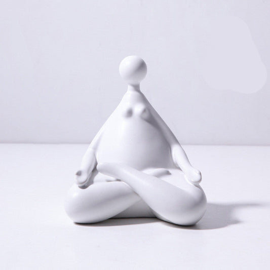 A pair of white ceramic figurines, one sitting and one standing, placed on top of a stack of books with a decorative vase beside them.