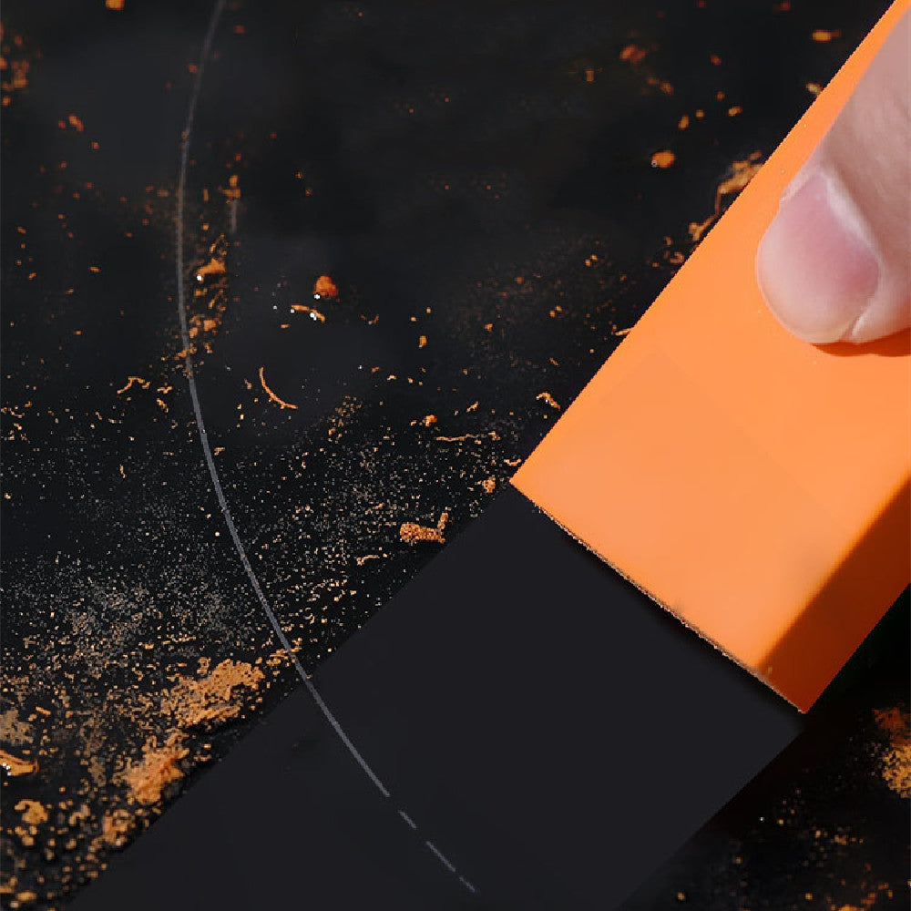 Orange eraser on a black surface with orange dust