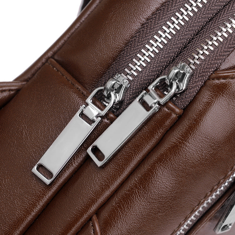 Close-up of a brown leather bag with silver zippers on a white background