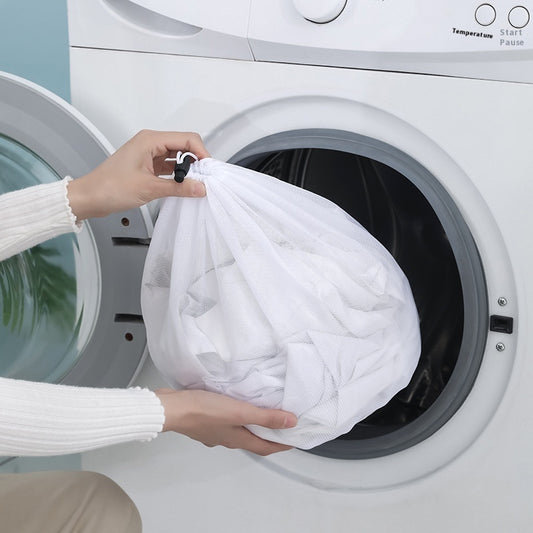 Person holding a white comforter over an open washing machine.