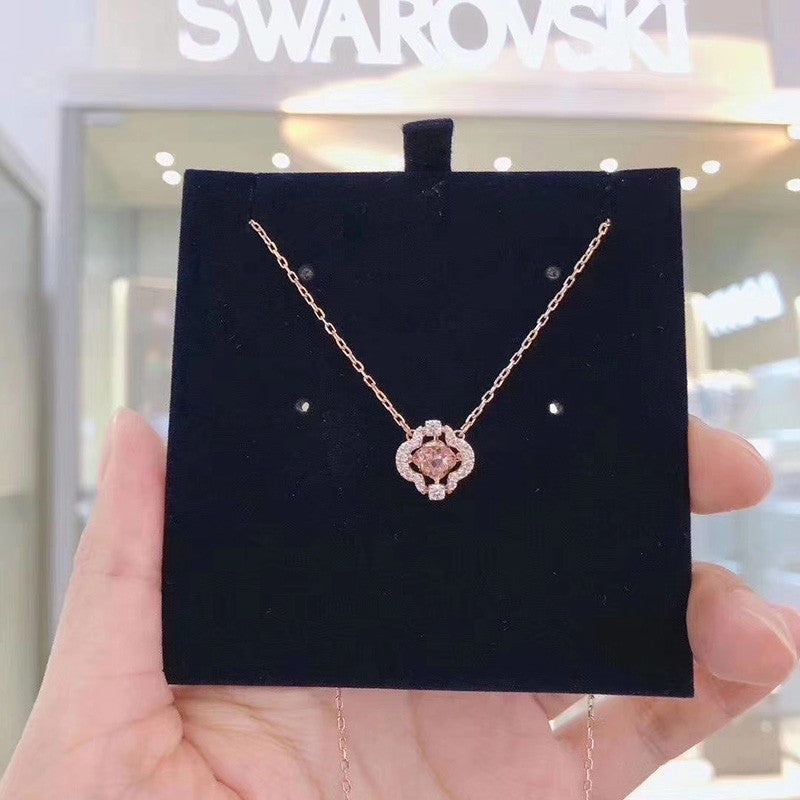 Swarovski necklace on a black display card held by a hand.