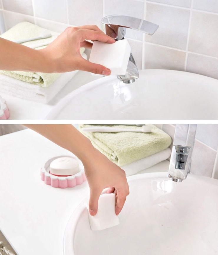 Hand using a white cleaning tool on a sink with a tiled wall background