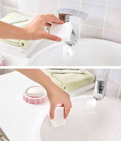 Hand using a white cleaning tool on a sink with a tiled wall background