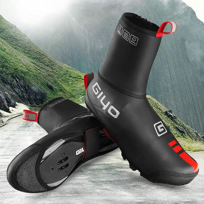 Black and red cycling shoe covers with GIYO branding on a mountain road background
