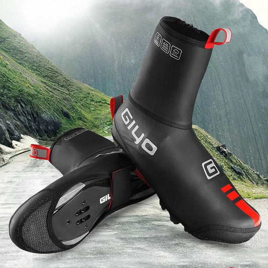 Black and red cycling shoe covers with GIYO branding on a mountain road background