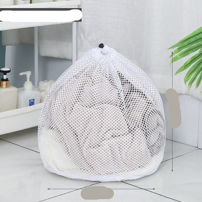 Two white mesh laundry bags filled with laundry standing in front of a washing machine with a person partially visible in the background.