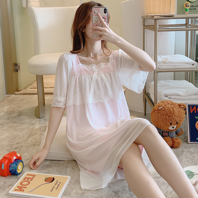 Woman in a white lace nightgown taking a selfie in a room with a teddy bear and toys.