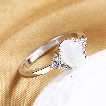 Silver ring with a large central gemstone and smaller stones on a beige fabric background