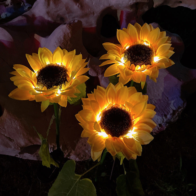 Three illuminated sunflower lights on a dark background
