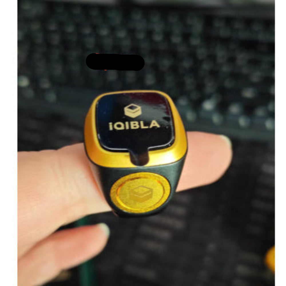 Gold and black device with 'IQIBLA' branding held by a hand against a blurred background