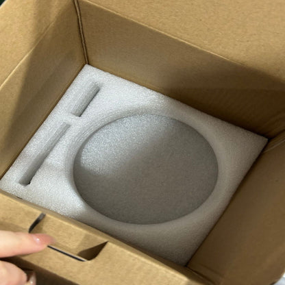 Round gray object in a cardboard box with foam padding