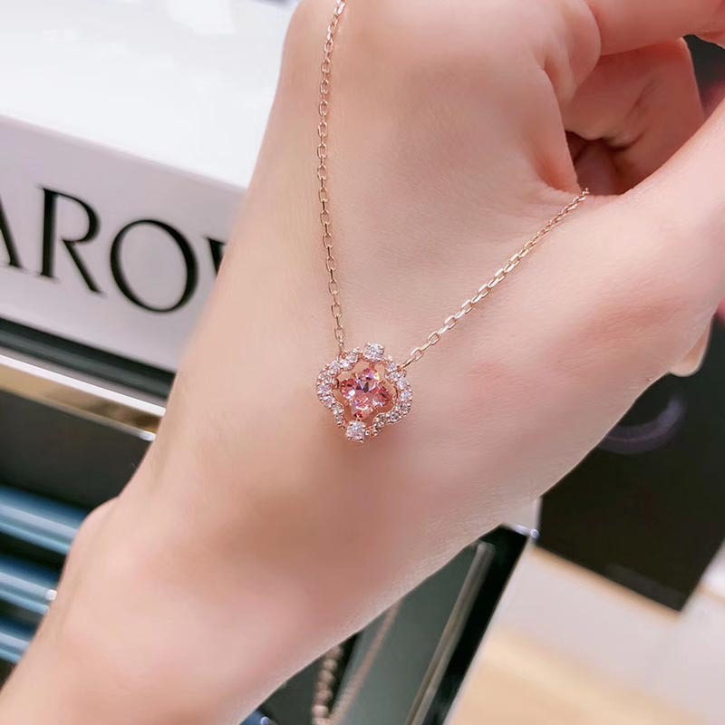 Hand wearing a delicate pink necklace with a blurred background