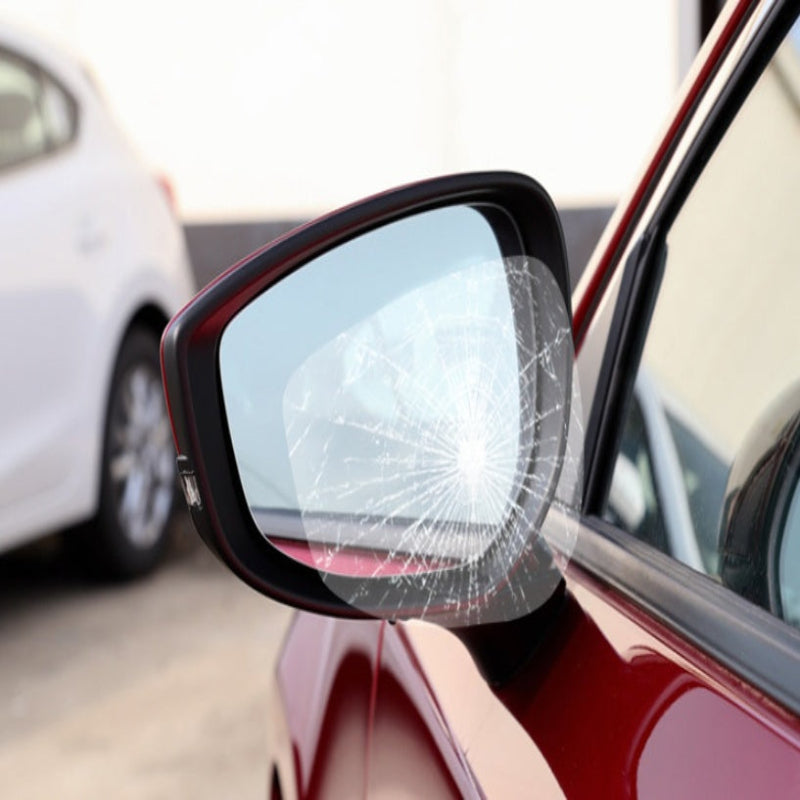 Car side mirror with a cracked glass panel, blurred background of a car and road.