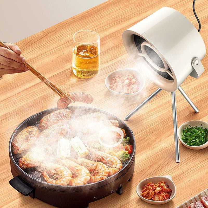 Person cooking seafood in a hot pot with a portable stove on a wooden table.