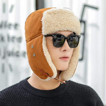 Person wearing a brown aviator hat with fur trim and sunglasses against a blurred background