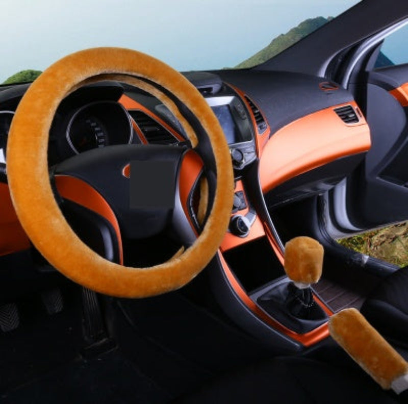 Car interior with orange steering wheel cover and dashboard trim.